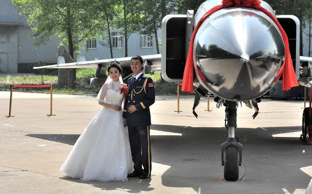 A soldier of China's Liberation Army (PLA) air force poses for pictures with his wife as they attend a group wedding in Anshan, Liaoning, China, May 21, 2016. (Photo by Reuters/Stringer)