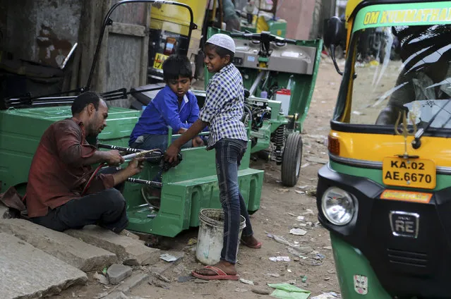 An Indian worker is helped by children to make a chassis for a three-wheeled vehicle at an industrial unit in Bangalore, India, Tuesday, May 31, 2016. India says its economy grew 7.6 percent in the financial year that ended March 31 and a swift 7.9 percent in the last quarter of the year keeping its position as the world's fastest growing major economy. (Photo by Aijaz Rahi/AP Photo)