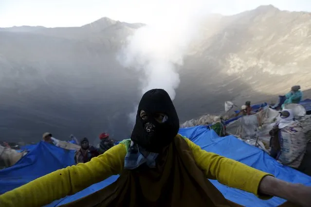 A villager holds onto a portion of a net while standing on the slope of the crater with others while waiting to catch offerings thrown by Hindu worshippers into the crater during the Kasada Festival at Mount Bromo in Probolinggo, Indonesia's East Java province, August 1, 2015. (Photo by Reuters/Beawiharta)