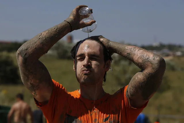 A participant stops to cool off during the Mud Day athletic event at El Goloso Military base on the outskirts of Madrid, Spain, Saturday, June 11, 2016. (Photo by Paul White/AP Photo)