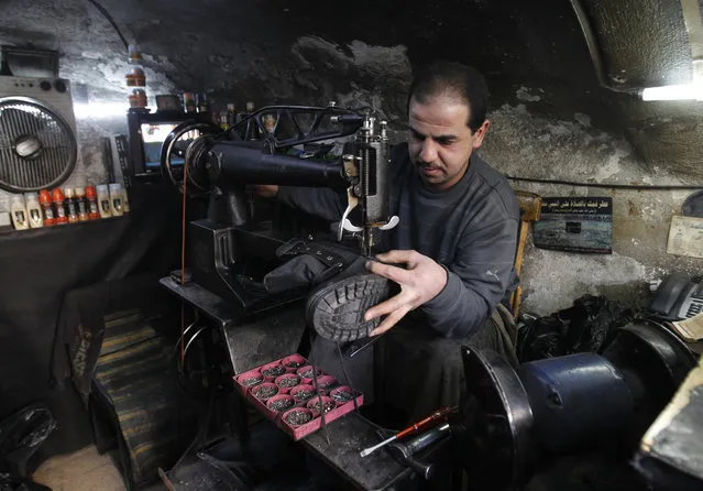 A Syrian cobbler repairs a military boot at his shop in Damascus February 9, 2014. (Photo by Khaled al-Hariri/Reuters)