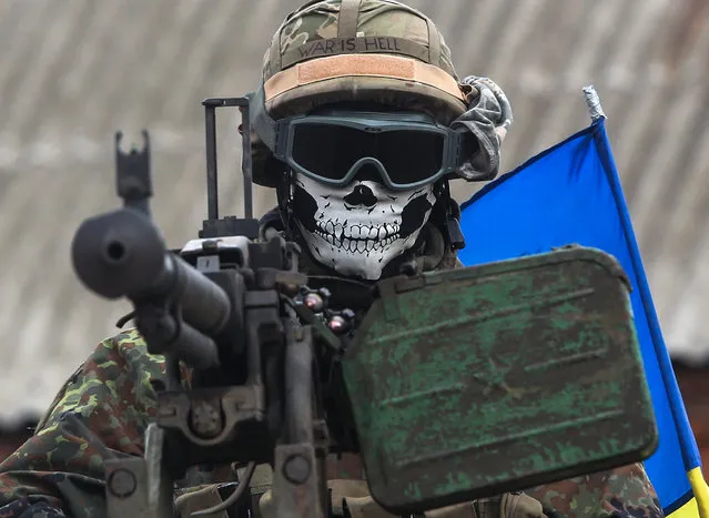 A masked Ukrainian serviceman, with the words “War is Hell” written on his helmet is seen on an armored military vehicle near the eastern city of Debaltseve, Ukraine, 23 September 2014. Pro-Russian separatists in eastern Ukraine said 22 September that a buffer zone along the front line with government forces will not be implemented soon. The nine-point agreement signed by separatist leaders and representatives of the Ukrainian government in the Belarusian capital of Minsk on 20 September stipulates that each side has to withdraw its heavy weapons 15 kilometres from the frontline. (Photo by Konstantin Grishin/EPA)