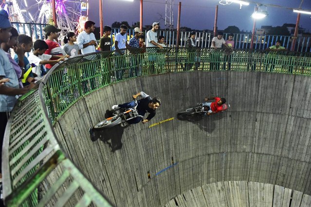 Stuntmen ride their motorbikes along the wall of a wooden structure during the 'Well of Death' show at a fair in Jalandhar on September 16, 2024. (Photo by Shammi Mehra/AFP Photo)