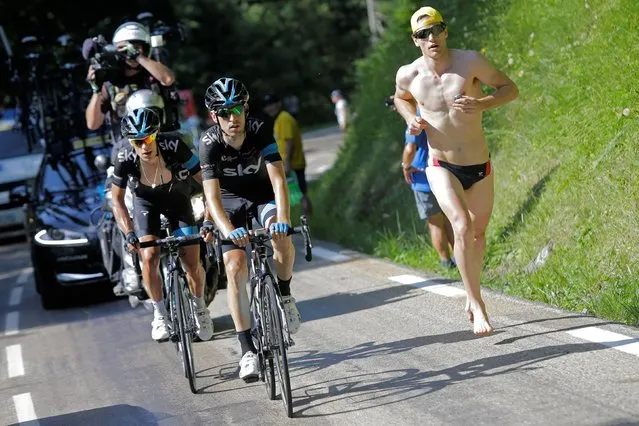 Australia's Richie Porte, left, follows teammate Spain's Mikel Nieve Iturralde as a man in swimsuit runs alongside after Porte was distanced by the pack during the thirteenth stage of the Tour de France cycling race over 197.5 kilometers (122.7 miles) with start in Saint-Etienne and finish in Chamrousse, France, Friday, July 18, 2014. (Photo by Laurent Cipriani/AP Photo)
