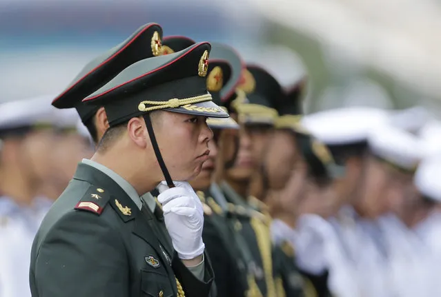 A member of honor guard adjusts his cap as he prepares for a welcoming ceremony outside the Great Hall of the People on a hot day in Beijing. (Photo by Jason Lee/Reuters)