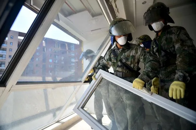 Paramilitary policemen take down broken window at an apartment near the site of the explosions at the Binhai new district, Tianjin, China, August 16, 2015. (Photo by Reuters/China Daily)