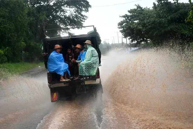 People sit in the back of a truck during heavy rain in Kytehto township, Mon state on August 12, 2019. Myanmar troops and emergency responders scrambled to provide aid in flood-hit parts of the country after rising waters forced residents to flee by boat and a landslide killed at least 52 people. (Photo by Ye Aung Thu/AFP Photo)