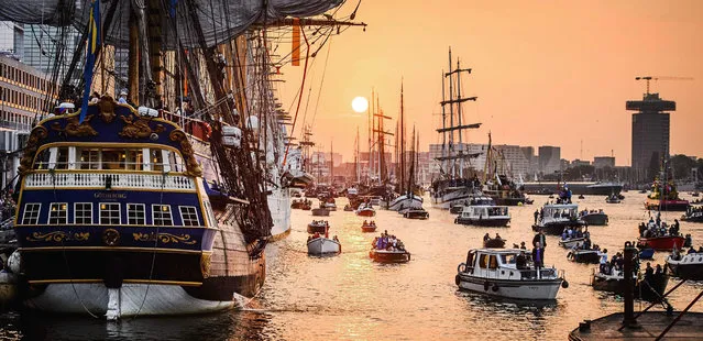 The sun goes down behind tall and  small ships at the IJ river in Amsterdam, the Netherlands, 19 August 2015, during the Sail 2015, a parade of ships that takes place every five years. (Photo by Remko De Waal/EPA)