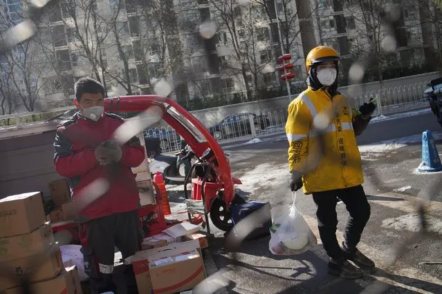 Meituan and JD.com delivery workers wearing face masks stand outside a residential compound where delivery workers are not allowed in as part of the measures to prevent and control the spread of coronavirus, in Beijing, China on February 8, 2020. (Photo by Reuters/China Stringer Network)