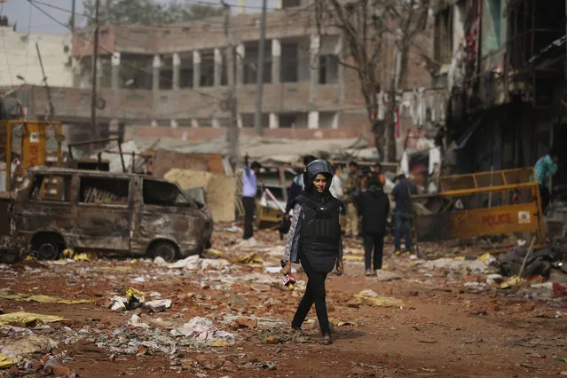 In this Thursday, February 27, 2020, a television reporter holds a microphone as she walks through a street vandalized in Tuesday's violence in New Delhi, India. (Photo by Altaf Qadri/AP Photo)
