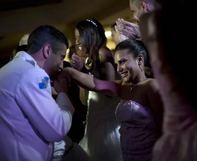 A police officer kisses the hand of a debutante. (Photo by Silvia Izquierdo/AP Photo via The Palm Beach Post)