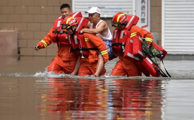A picture made available on 26 July 2016 shows rescuers carrying out an aged man in a flooded area in Shenyang, Liaoning province, northeast China, 25 July 2016. Downpours hit the city again Tuesday, flooding many areas in the city. (Photo by EPA/Stringer)