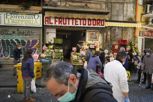 People buy fruit and vegetables at a shop in Naples, Monday, April 27, 2020. Region Campania allowed cafes and pizzerias to reopen for delivery Monday, as Italy it is starting to ease its lockdown after a long precautionary closure due to the coronavirus outbreak. (Photo by Andrew Medichini/AP Photo)