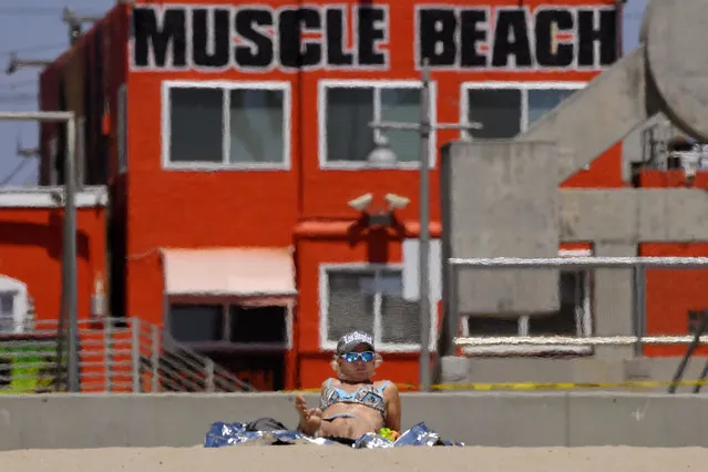 A sunbather lays out at Venice Beach during the coronavirus outbreak, Wednesday, May 13, 2020, in Los Angeles. Los Angeles County reopened its beaches Wednesday in the latest cautious easing of coronavirus restrictions that have closed most California public spaces and businesses for nearly two months. (Photo by Mark J. Terrill/AP Photo)