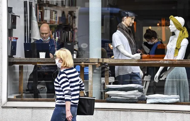 A customer sits with his laptop beside display mannequins at the Cafe Livres in Essen, Germany, Wednesday, May 20, 2020. The cafe set the dolls as placeholders on various places for more distance between customers due to the new coronavirus orders for restaurants and cafes. (Photo by Martin Meissner/AP Photo)