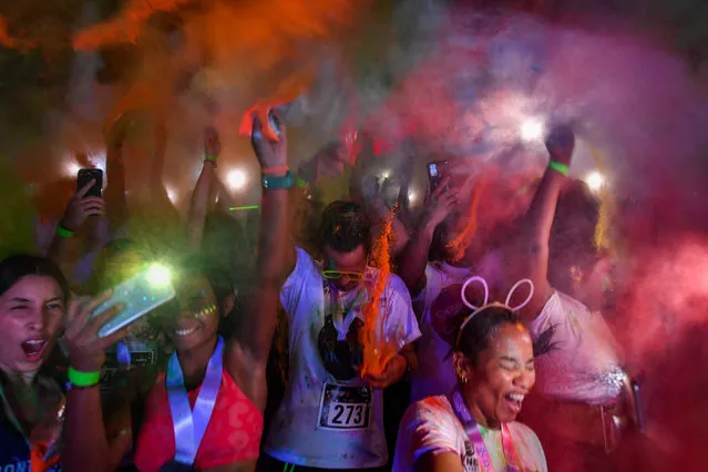 Runners covered in coloured powder dance after taking part in the five-kilometre Night Color Run at the Simon Bolivar Park in Caracas, on Septembre 17, 2022. (Photo by Federico Parra/AFP Photo)