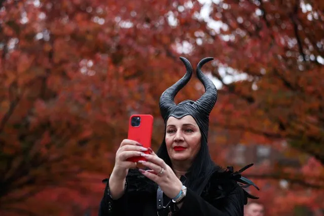 A person in a costume of Maleficent takes a selfie in front of fall foliage on Halloween in Manhattan, New York City, U.S., October 31, 2022. (Photo by Andrew Kelly/Reuters)