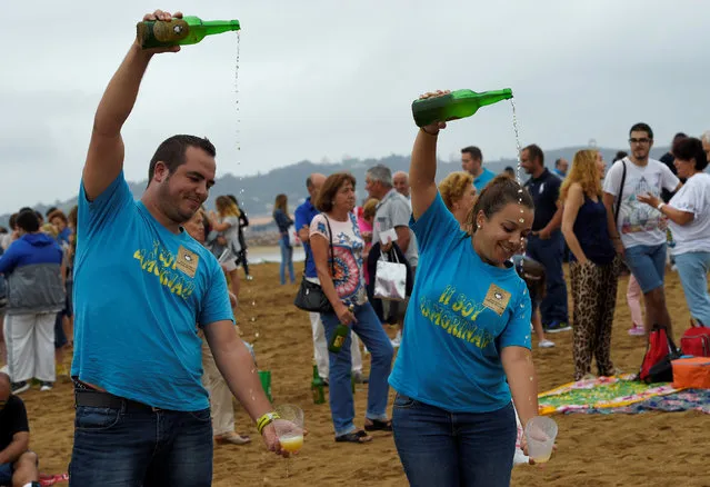 People take part in trying to beat the world record of people simultaneously pouring cider during the annual Fiesta de la Sidra Natural (Natural Cider Party Festival) in Gijon, northern Spain, August 26, 2016. (Photo by Eloy Alonso/Reuters)