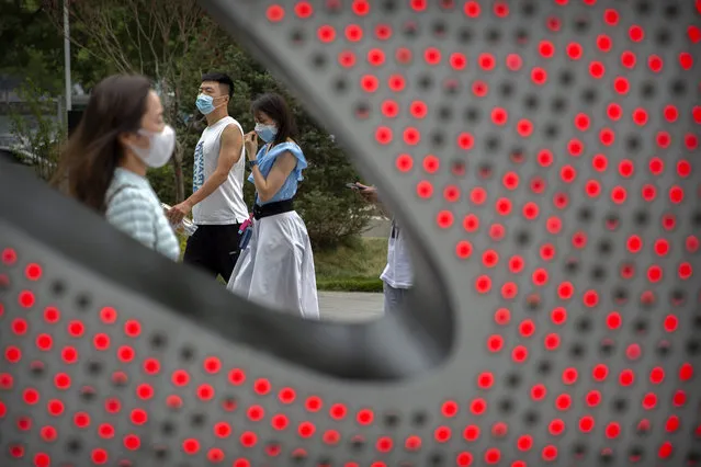 People wearing face masks to protect against the spread of the new coronavirus walk through a shopping and office complex in Beijing, Wednesday, June 24, 2020. New virus cases have declined in China and in the capital Beijing, where a two-week spike appears to be firmly waning. (Photo by Mark Schiefelbein/AP Photo)