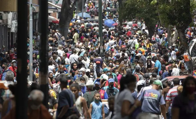 People, some wearing face masks as a measure to curb the spread of the new coronavirus, walk in the Catia neighborhood of Caracas, Venezuela, Saturday, June 20, 2020, during a relaxation of restrictive measures amid the new coronavirus pandemic. (Photo by Ariana Cubillos/AP Photo)