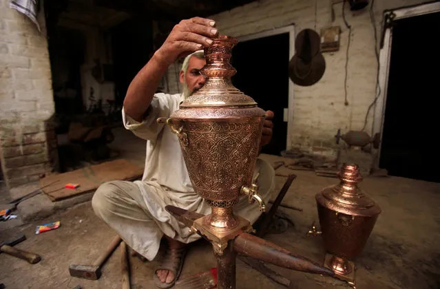 A craftsman puts final touches to a decoration piece of tea kettle, at a workshop in Peshawar, Pakistan, August 17, 2016. (Photo by Fayaz Aziz/Reuters)