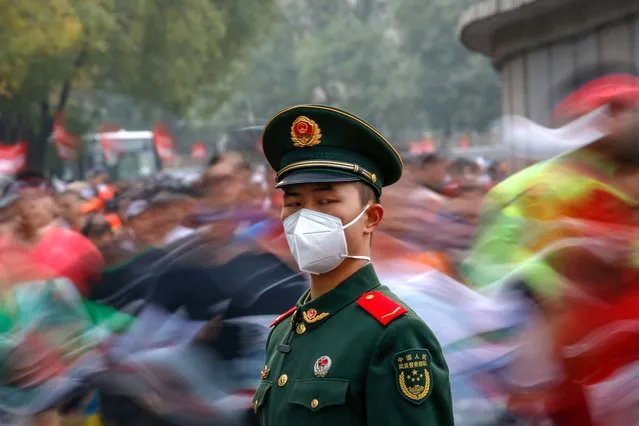 A soldier stands guard as runners compete during the Beijing Marathon in Beijing, China, 06 November 2022. The Beijing Marathon resumed after a two year hiatus following the COVID-19 pandemic. Participants were limited and were required to follow strict COVID-19 protocols before being able to join the race. (Photo by Mark R. Cristino/EPA/EFE/Rex Features/Shutterstock)