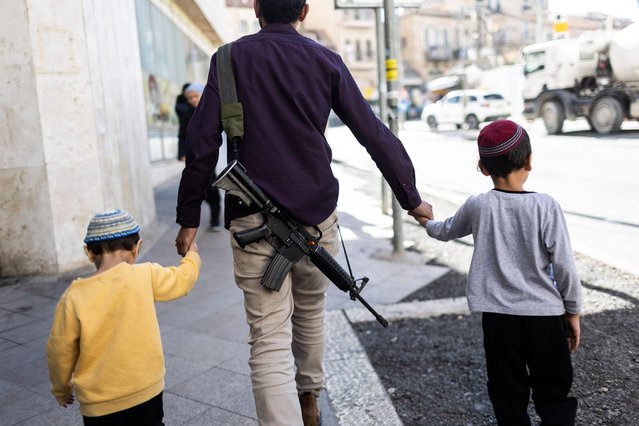 A man carrying an assault rifle walks the street with his kids in Jerusalem, 10 January 2024. Since the 07 October 2023 Hamas attacks, the Israel Defense Forces (IDF) has recruited more than 300,000 reservists soldiers, while over 260,000 new applications for weapons licenses have been submitted to the Ministry of Internal Security office, the minister of national security said. The events of October 2023 had a huge impact on Israeli citizens and their sense of personal security. (Photo by Abir Sultan/EPA/EFE)