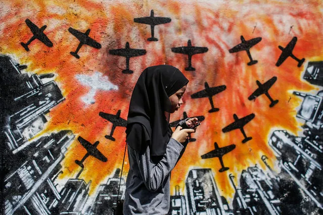 A woman passes by a work of art featured in the street art project “Laman Seni” in Shah Alam, Malaysia, 05 December 2017. Laman Seni is organized by a local council and aims to redefine un-used and un-utilized spaces and encourage creativity among youth and student artist, as well as and make a useable space for the community while enhancing the urban condition, to improve the standard of life in the neighborhood where the art is displayed. (Photo by Fazry Ismail/EPA/EFE)