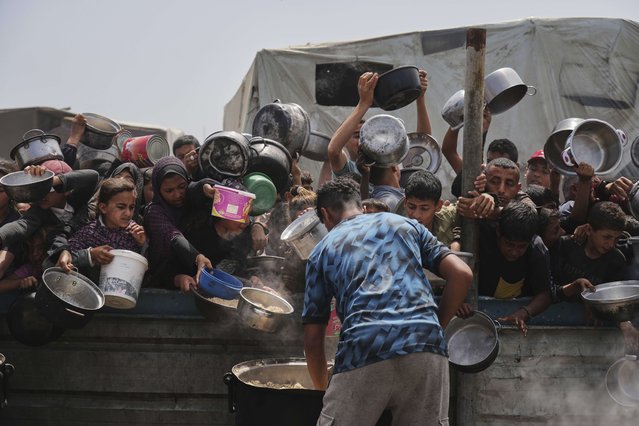 Palestinian children receive donated food at a distribution center in Khan Younis, Gaza Strip, Monday, April 21, 2025. (Photo by Abdel Kareem Hana/AP Photo)