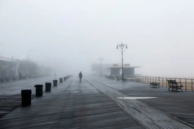 A man walks on the Coney Island Boardwalk during a foggy morning in the Brooklyn borough of New York City, U.S., October 25, 2022. (Photo by Shannon Stapleton/Reuters)