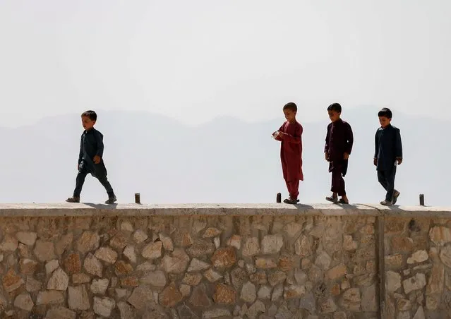 Afghan boys walk on a wall during the Muslim festival of Eid al-Adha, amid the spread of the coronavirus disease (COVID-19), in Kabul, Afghanistan on July 31, 2020. (Photo by Mohammad Ismail/Reuters)