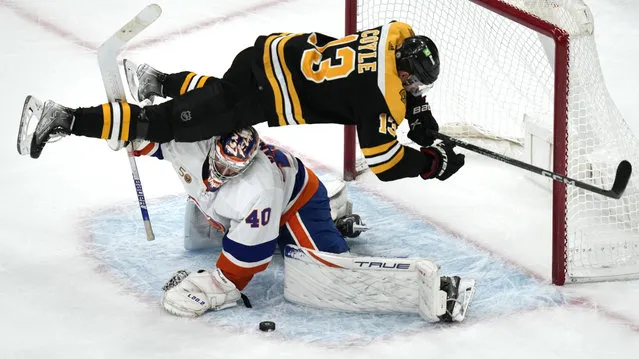 Boston Bruins center Charlie Coyle (13) goes airborne as New York Islanders goaltender Semyon Varlamov (40) makes the save in a shootout during an NHL hockey game, Tuesday, December 13, 2022, in Boston. (Photo by Charles Krupa/AP Photo)
