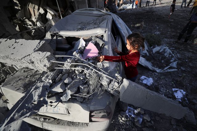 A Palestinian girl scribbles on a damaged car at the site of an Israeli strike on a house, in Jabalia, in the northern Gaza Strip on May 14, 2025. (Photo by Mahmoud Issa/Reuters)
