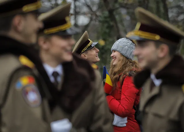 A couple shares a laugh as troops wait for the start of the national day military parade in Bucharest, Romania, Friday, December 1, 2017. Thousands of Romanian troops staged a military parade to celebrate Romania's national day, but key politicians didn't attend, signaling tensions between the president and the ruling left-wing coalition over plans to revamp the justice system. (Photo by Vadim Ghirda/AP Photo)