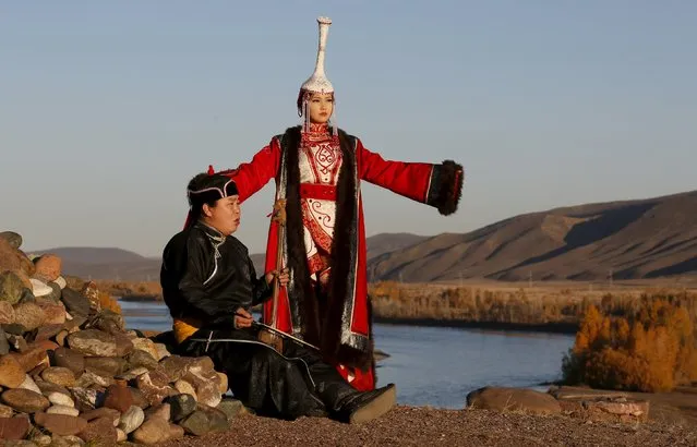 Master of throat singing (or Khoomei) Aikhan Orzhak (L) and model Choigana Kertek, dressed in traditional costume, perform during sunset at the Aldyn Bulak area on the bank of the Yenisei River outside the village of Ust-Elegest in Tuva region, Southern Siberia, Russia, October 7, 2015. The region is inhabited by Tuvans, historically cattle-herding nomads, who nowadays practise two main confessions - Buddhism and Shamanism. (Photo by Ilya Naymushin/Reuters)