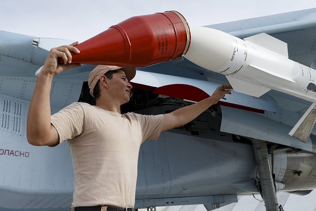 A Russian ground staff member loads a Sukhoi Su-30 fighter jet with weapons at the Hmeymim air base near Latakia, Syria, in this handout photograph released by Russia's Defence Ministry October 22, 2015. (Photo by Reuters/Ministry of Defence of the Russian Federation)