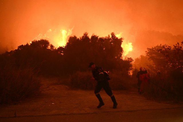 Firefighters work to extinguish a wildfire near the city of Patras, western Greece on August 13, 2025. Greece on August 13, 2025 battled to contain more than 20 wildfires including one menacing its third-largest city Patras as a heatwave stoked blazes and forced the evacuation of thousands in southern Europe. (Photo by Aris Messinis/AFP Photo)