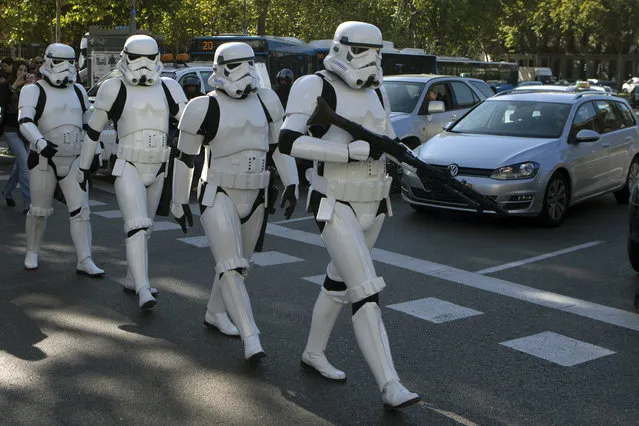 Star Wars Storm Trooper characters cross the street after a giant Star Wars helmet was unveiled, during the inauguration of an open air exhibition called 'Face the Force' in Madrid, Spain, Friday, October 30, 2015. Seven other giant helmets are due to be placed in various corners in the city. (Photo by Paul White/AP Photo)