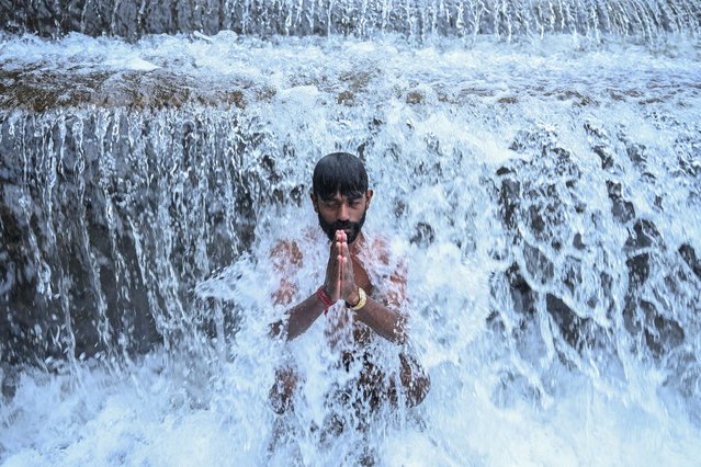 A devotee takes a holy dip in the Bagmati River before offering prayers to the Hindu god Shiva at the Pashupatinath Temple during Shravan festivities on the outskirts of Kathmandu on August 4, 2025. (Photo by Prakash Mathema/AFP Photo)