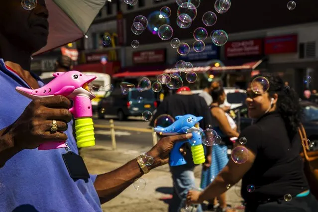 A street vendor blows bubbles on the street in a region of the South Bronx that has seen a deadly outbreak of Legionnaires' disease in New York August 7, 2015. (Photo by Lucas Jackson/Reuters)