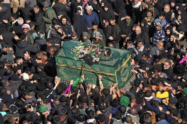 Shiite worshippers carry a symbolic coffin at the golden-domed shrine of Imam Moussa al-Kadhim, who died at the end of the 8th century, during the annual commemoration of his death in Baghdad, Iraq, Friday, Feb.ruary 17, 2023. (Photo by Hadi Mizban/AP Photo)