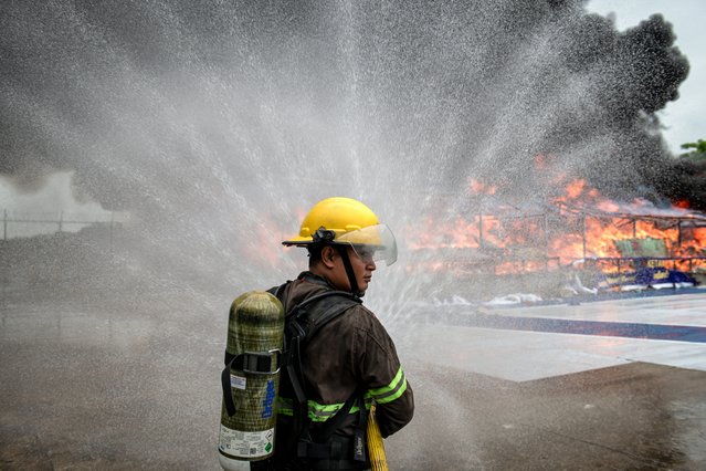 A firefighter sprays water to control burning pile of seized illegal drugs during a destruction ceremony to mark the “International Day against Drug Abuse and Illicit Trafficking” in Yangon on June 26, 2025. (Photo by Sai Aung Main/AFP Photo)