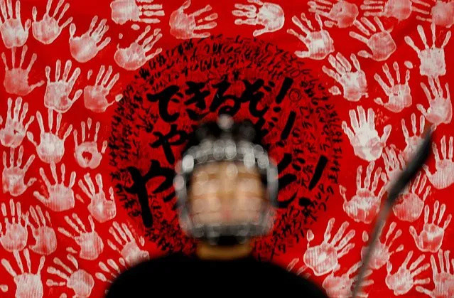 An athlete of Japan practices below a banner made of the teams' handprints ahead of the 2022 Beijing Winter Olympics at Wukesong Sports Centre in Beijing, China on February 2, 2022. (Photo by Jonathan Ernst/Reuters)