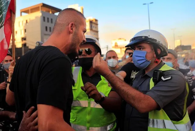 A traffic policeman asks an angry anti-government protester to reopen the main highway that links Beirut with north Lebanon during a protest against rising prices and worsening economic and financial conditions, in Zalka, north of Beirut, Lebanon, Monday, October 5, 2020. Lebanon is passing through its worst economic and financial crisis in decades made worse by the coronavirus pandemic. (Photo by Hussein Malla/AP Photo)