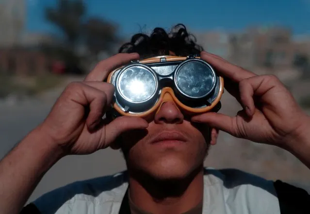 A man wears a protective glass to observe a partial solar eclipse in Sana'a, Yemen, 25 October 2022. A partial solar eclipse occurs when a portion of the earth is engulfed by the shadow (penumbra) cast by the moon as it passes between our planet and the sun in imperfect alignment. (Photo by Yahya Arhab/EPA/EFE/Rex Features/Shutterstock)