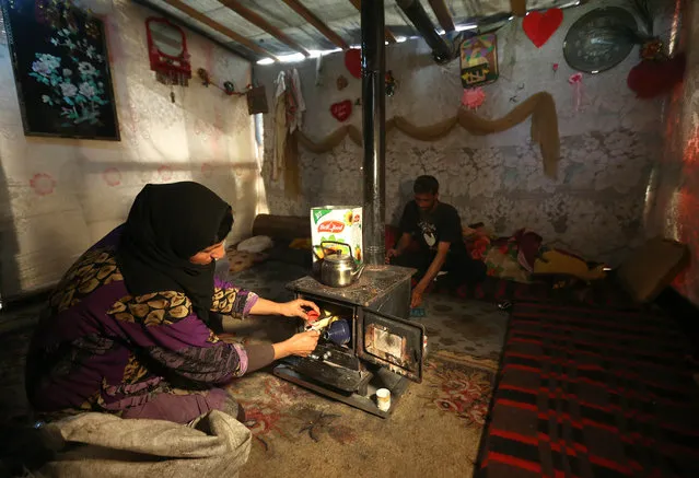 A Syrian woman lights a stove inside her tent at a refugee camp in Deir Zannoun village, Bekaa valley, Lebanon, Tuesday, January 6, 2015. (Photo by Hussein Malla/AP Photo)