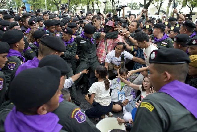 Thai police officers scuffle with pro-democracy supporters and journalist and surround pro-democracy leaders Nuttaa Mahattana, seated with her hands raised, and others during a protest march to mark the fourth anniversary of the military take-over of government in Bangkok, Thailand, Tuesday, May 22, 2018. Police in the Thai capital deployed about 3,200 officers to block a march by about 200 demonstrators, and arrested several leaders including Mahattana for protesting four years of military rule and calling for elections this year. (Photo by Gemunu Amarasinghe/AP Photo)