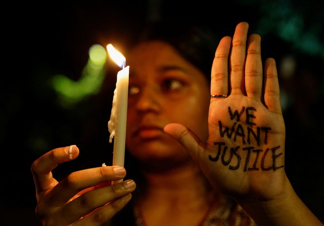A woman holds a candle during a vigil condemning the rape and murder of a trainee medic at a government-run hospital in Kolkata, on a street in Mumbai, India, on August 14, 2024. (Photo by Francis Mascarenhas/Reuters)