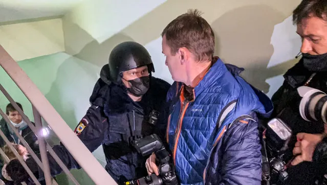 A police officer pushes photographers from a door of the apartment where Oleg Navalny, brother of jailed opposition leader Alexei Navalny lives in Moscow, Russia, Wednesday, January 27, 2021. Police are searching the Moscow apartment of jailed Russian opposition leader Alexei Navalny, another apartment where his wife is living and two offices of his anti-corruption organization. Navalny's aides reported the Wednesday raids on social media. (Photo by Mstyslav Chernov/AP Photo)