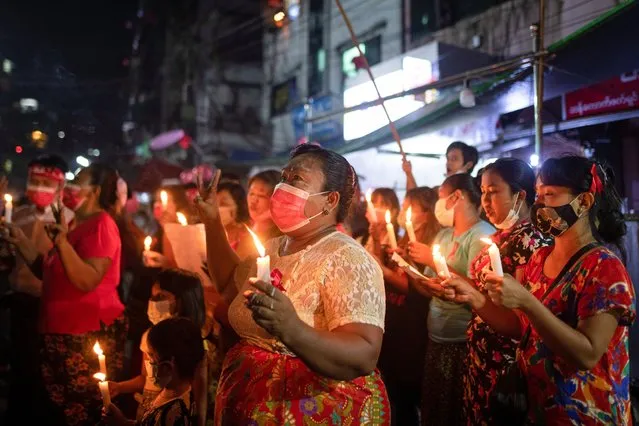 Women wearing red ribbons hold candles during a night protest against the military coup in Yangon, Myanmar on February 5, 2021. (Photo by Reuters/Stringer)